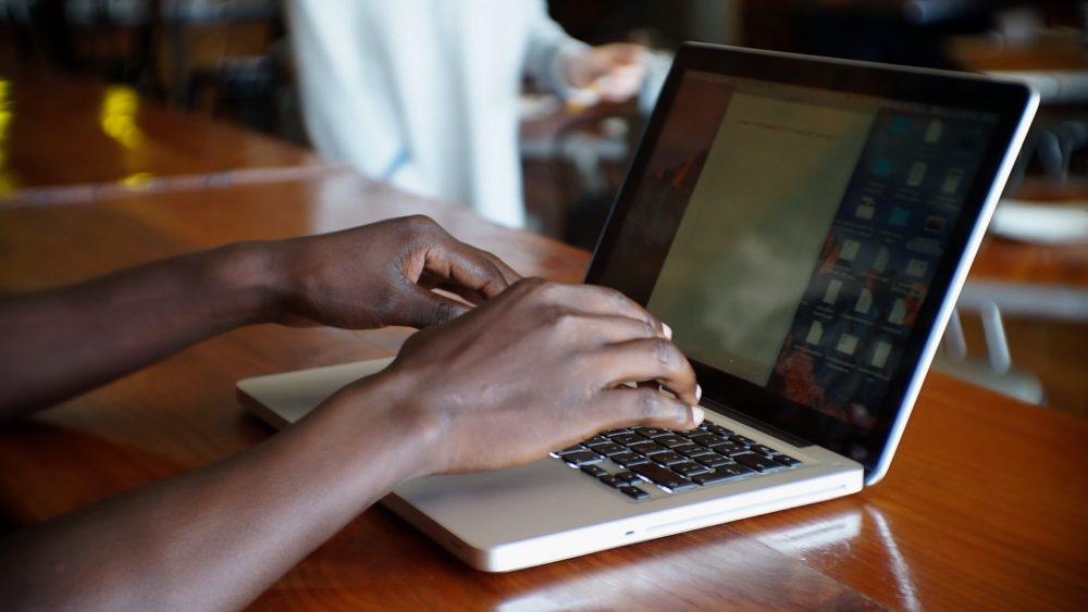 African-stock-video-of-a-black-African-man-sitting-at-a-restaurant-typing-on-his-laptop-computer